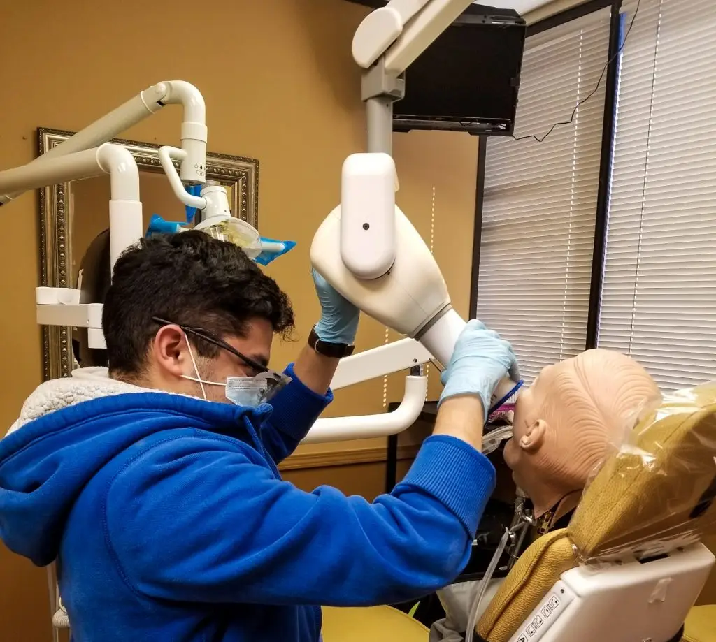 Student positioning an X-ray unit on a patient simulator