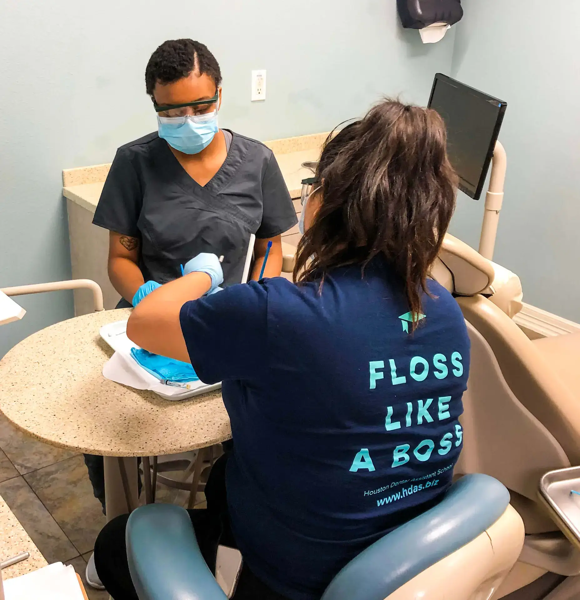 Two dental assistant students working chairside in a dental office